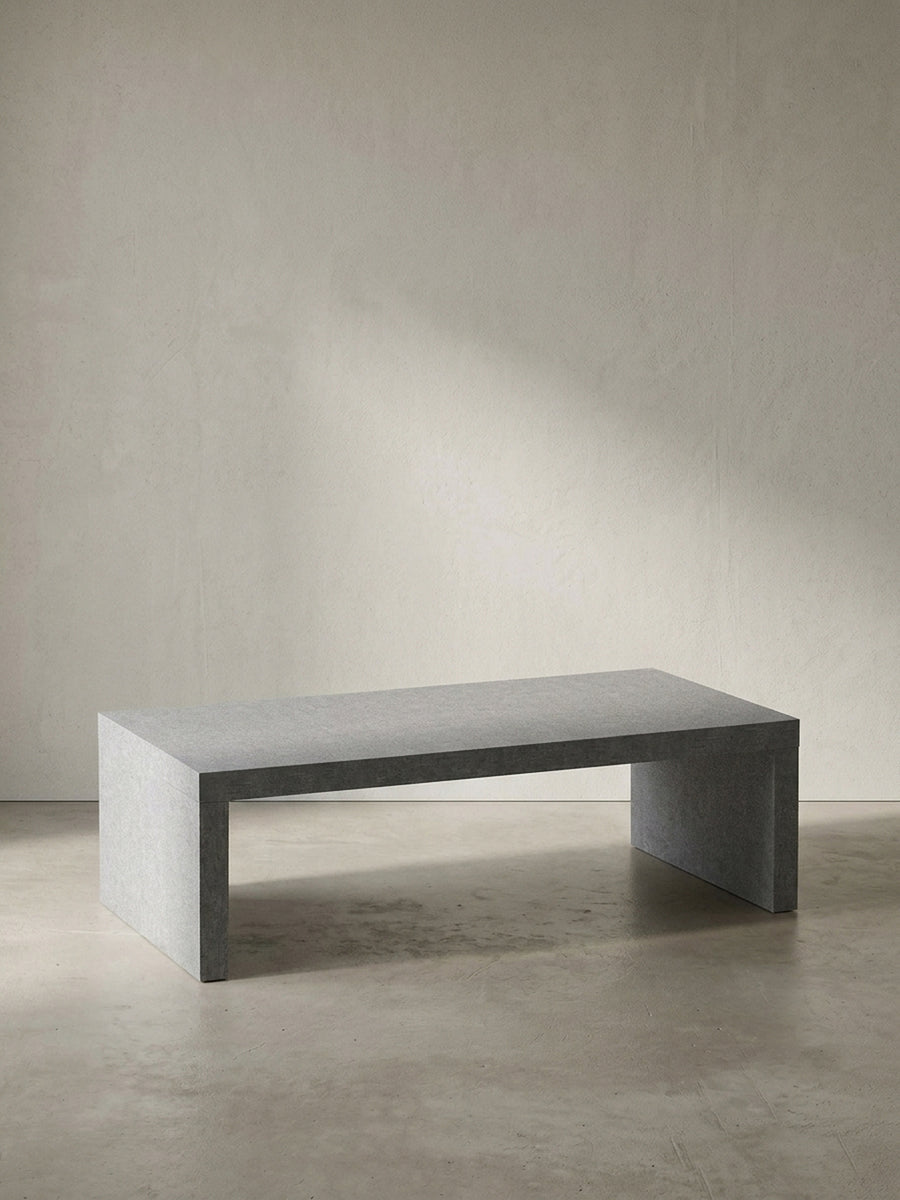 Grauer Couchtisch in klarer Beton-Optik mit den kompakten Maßen 110x55x35 cm frontal vor einem neutralen, reinweißen Hintergrund_