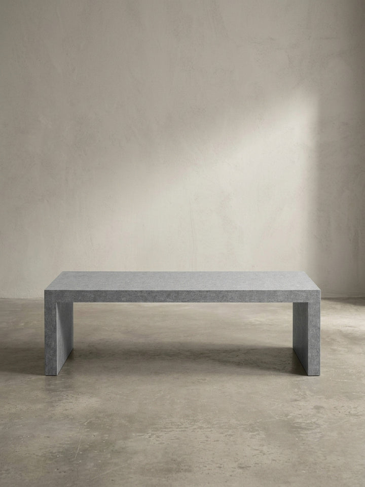 Freistehender Loungetisch aus MDF in kühlem Grau aus leicht seitlicher Perspektive, die die markante 5 cm dicke Materialstärke der Tischplatte betont_