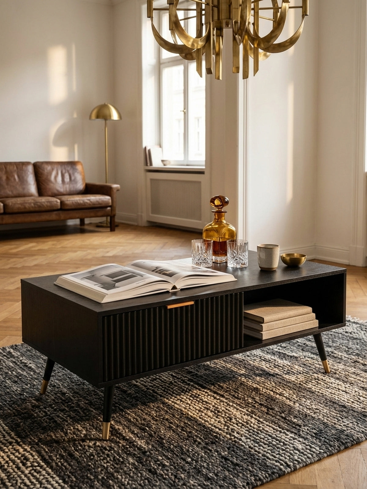Ein Stapel Architekturbücher und eine Whiskey-Karaffe arrangiert auf dem schwarzen Couchtisch, der eine gemütliche und intellektuelle Atmosphäre schafft.