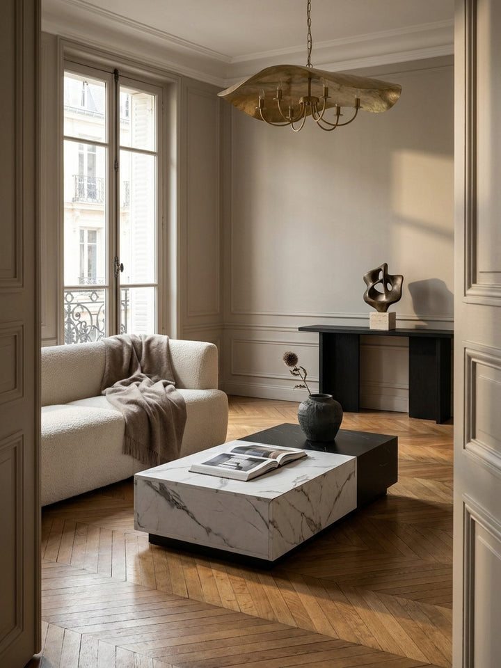 Moderner Couchtisch in Schwarz-Weiß-Marmoroptik als Herzstück eines eleganten Wohnzimmers mit Fischgrätparkett und einem beigen Bouclé-Sofa._