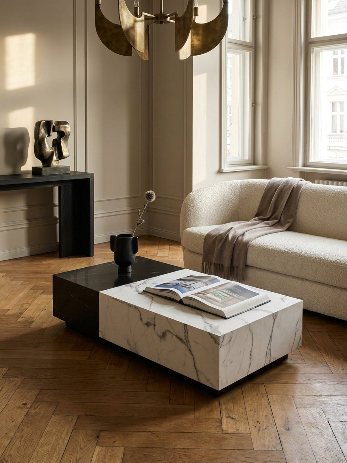 Der niedrige Wohnzimmertisch in Marmor-Optik harmoniert perfekt mit einem cremefarbenen Ecksofa und einem Beistelltisch aus dunklem Holz.