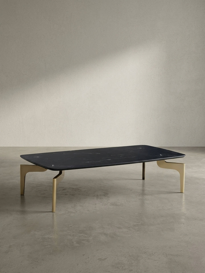 Flacher Couchtisch mit 120 cm Länge in schwarzer Marmor-Optik und pulverbeschichteten goldenen Beinen freigestellt vor neutralem weißem Hintergrund_