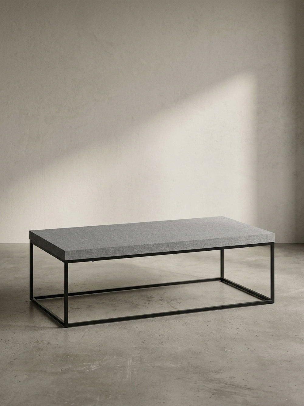 Moderner Couchtisch 120x60 cm mit grauer Platte in Betonoptik und filigranem schwarzem Metallgestell, freigestellt vor weißem Hintergrund._