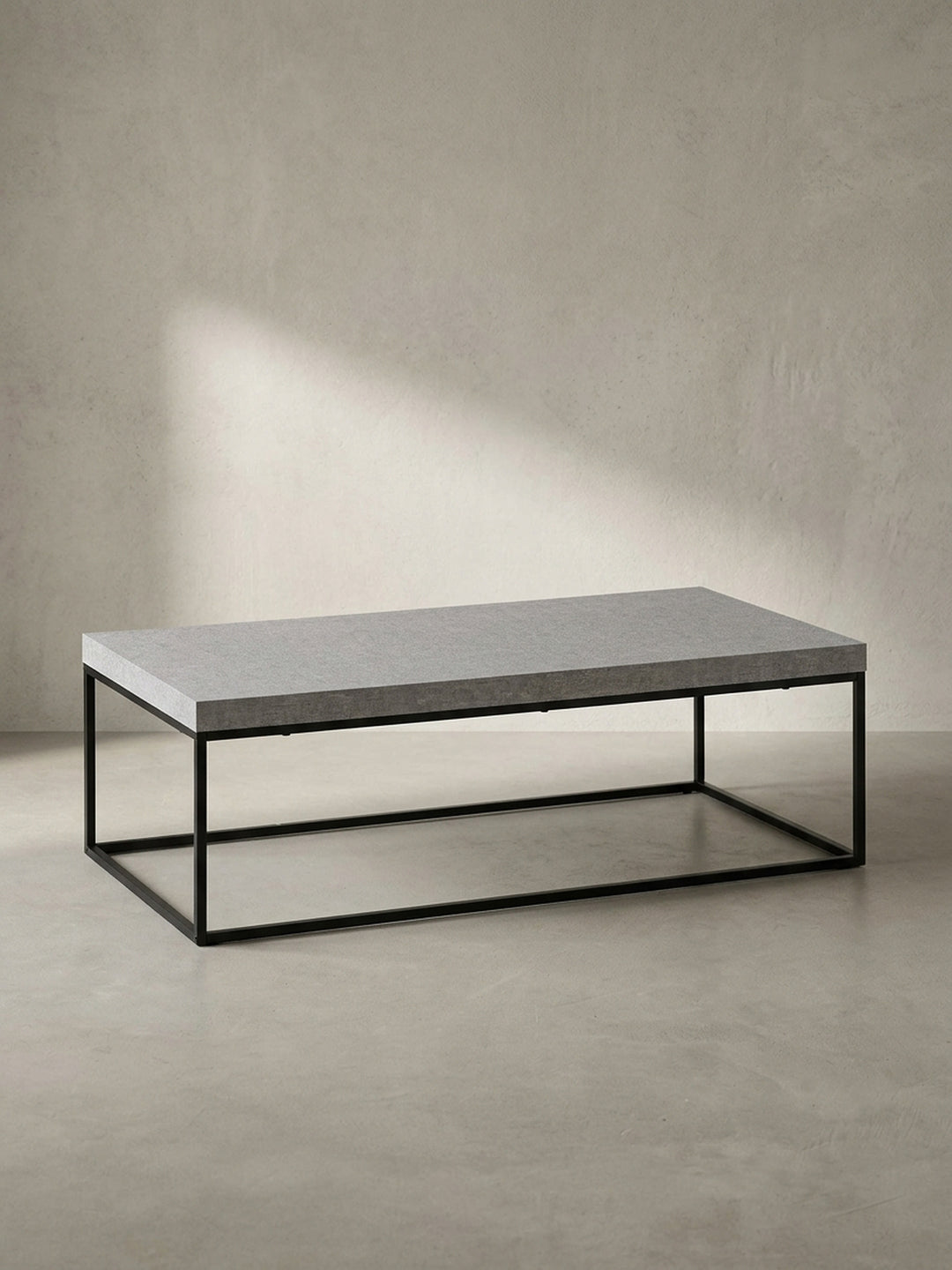Der Wohnzimmertisch in seiner Gesamtform, eine klare geometrische Silhouette aus einer grauen Platte und einem schwarzen Eisengestell._