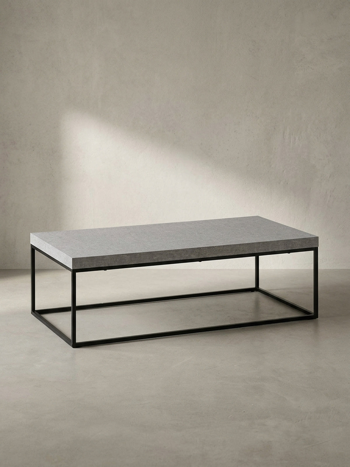 Der Wohnzimmertisch in seiner Gesamtform, eine klare geometrische Silhouette aus einer grauen Platte und einem schwarzen Eisengestell._