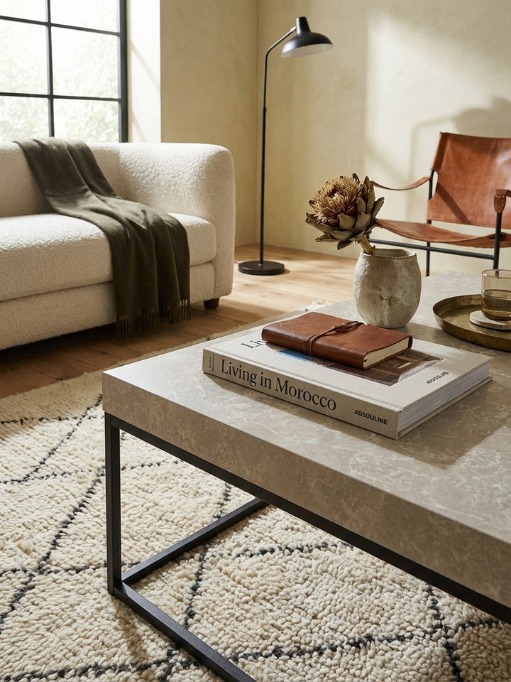 Detailaufnahme der sandfarbenen Tischplatte in Stein-Optik, die feine, marmorierte Maserung und die matte Oberfläche des modernen Couchtisches zeigend._