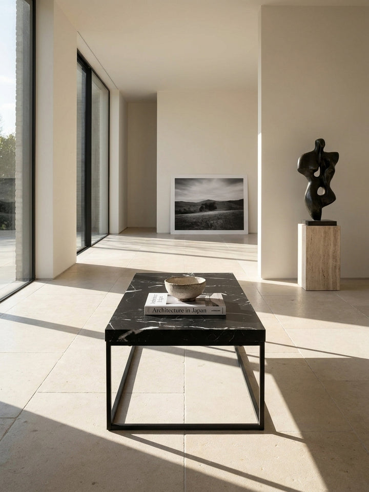 Schwarzer Couchtisch in Marmor-Optik 120x60x38 cm als eleganter Mittelpunkt in einem minimalistischen Wohnzimmer mit hellen Kalksteinböden und großen architektonischen Fenstern_