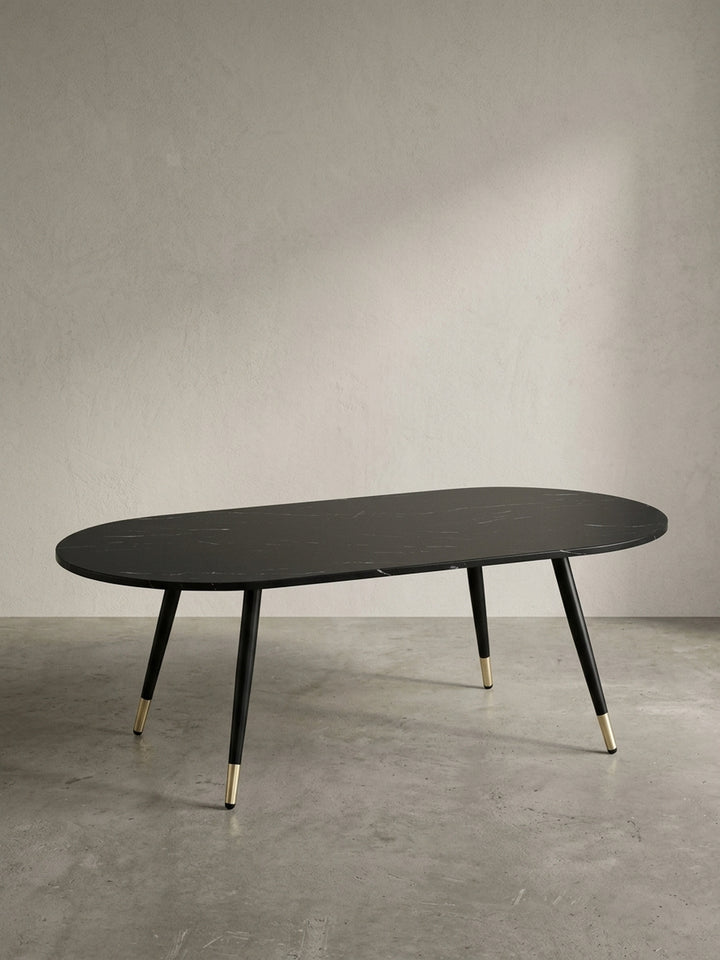 Ovaler Couchtisch 120x60x41,5 cm mit schwarzer Marmor-Dekor-Platte und konischen Metallbeinen freigestellt vor neutralem weißem Hintergrund._
