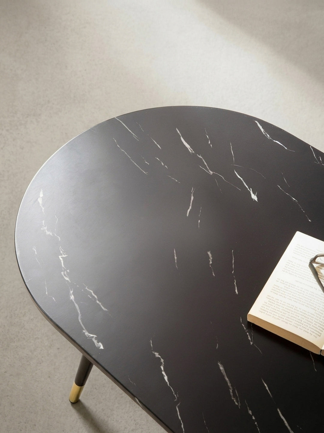 Frontale Perspektive auf den schwarzen Tisch in Marmoroptik der durch sein minimalistisches Design als eleganter Mittelpunkt im Raum wirkt._