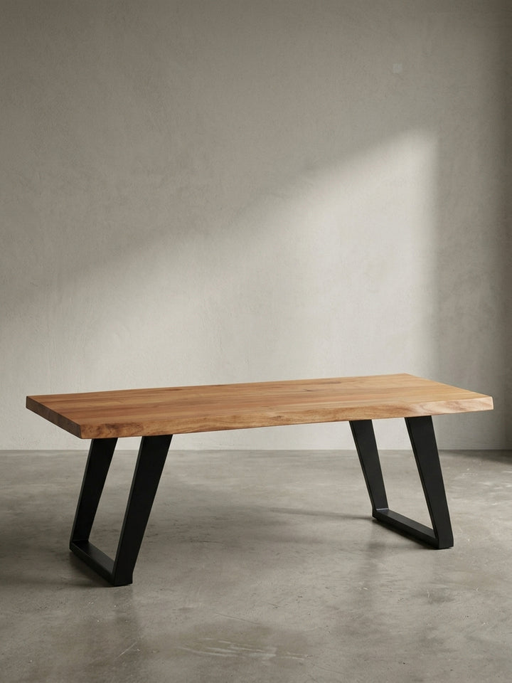 Frontansicht des Design-Wohnzimmertisches aus Akazie Massivholz mit charakteristischer Baumkante und stabilen schwarzen U-Form-Beinen, freigestellt._