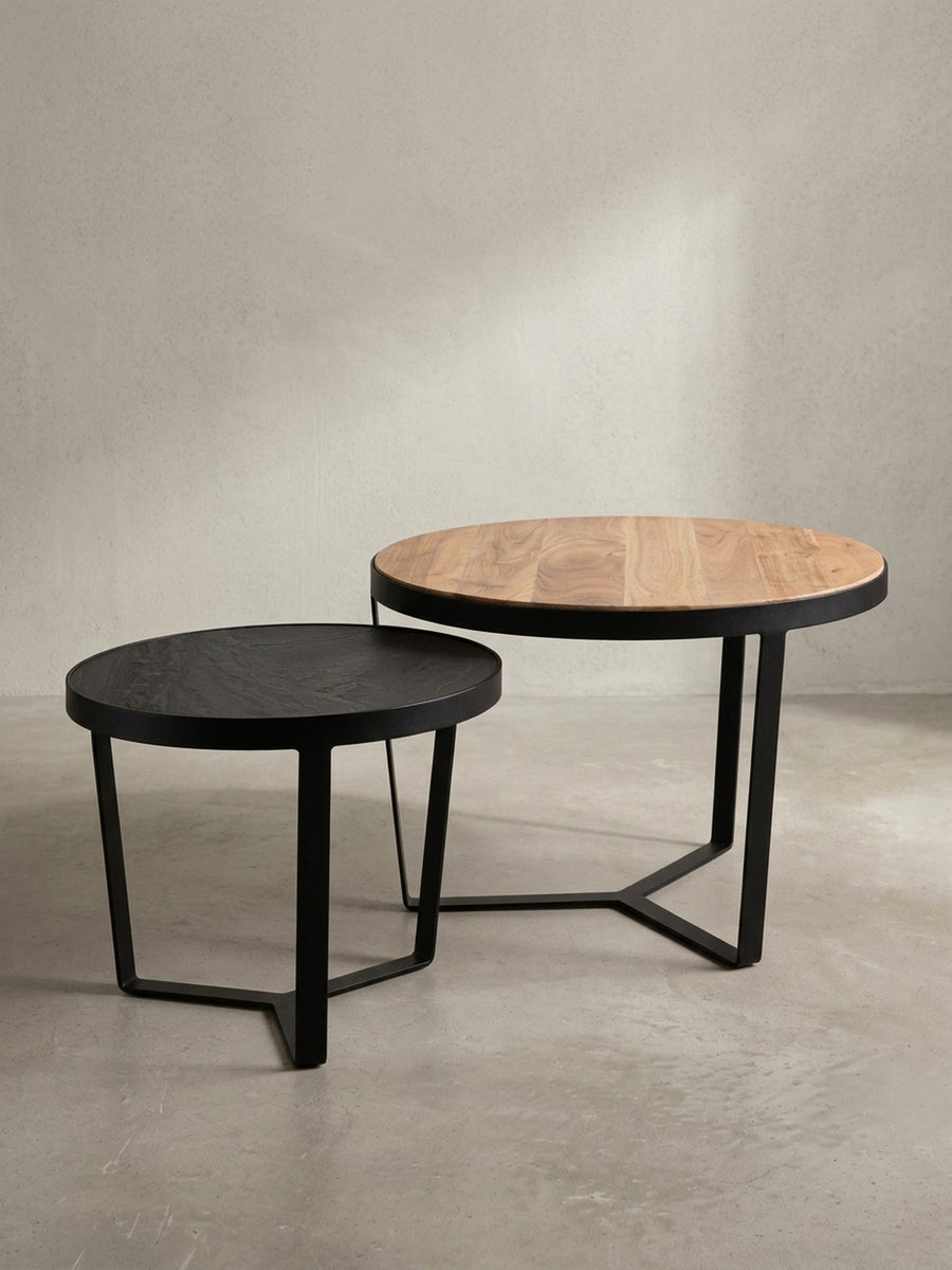 Runder Satztisch aus zwei Tischen in 3/4-Ansicht, die Materialkombination von Massivholz und dunkler Steinoptik ist klar erkennbar._