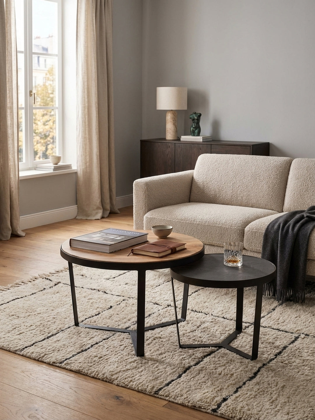 Verschachtelungstisch aus Holz und Metall neben einem bequemen Bouclé-Sofa, eine harmonische Kombination für das moderne Wohnzimmer._