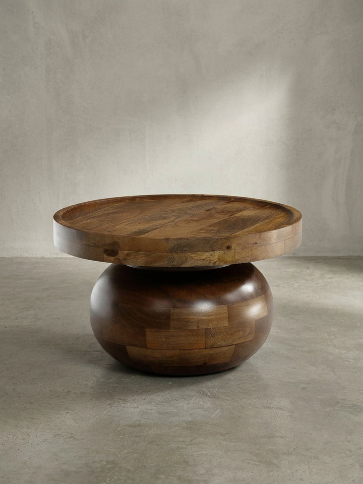 Vorderansicht des runden Couchtisches aus massivem Mangoholz mit skulpturalem, bauchigem Fuß und walnussfarbener Oberfläche._