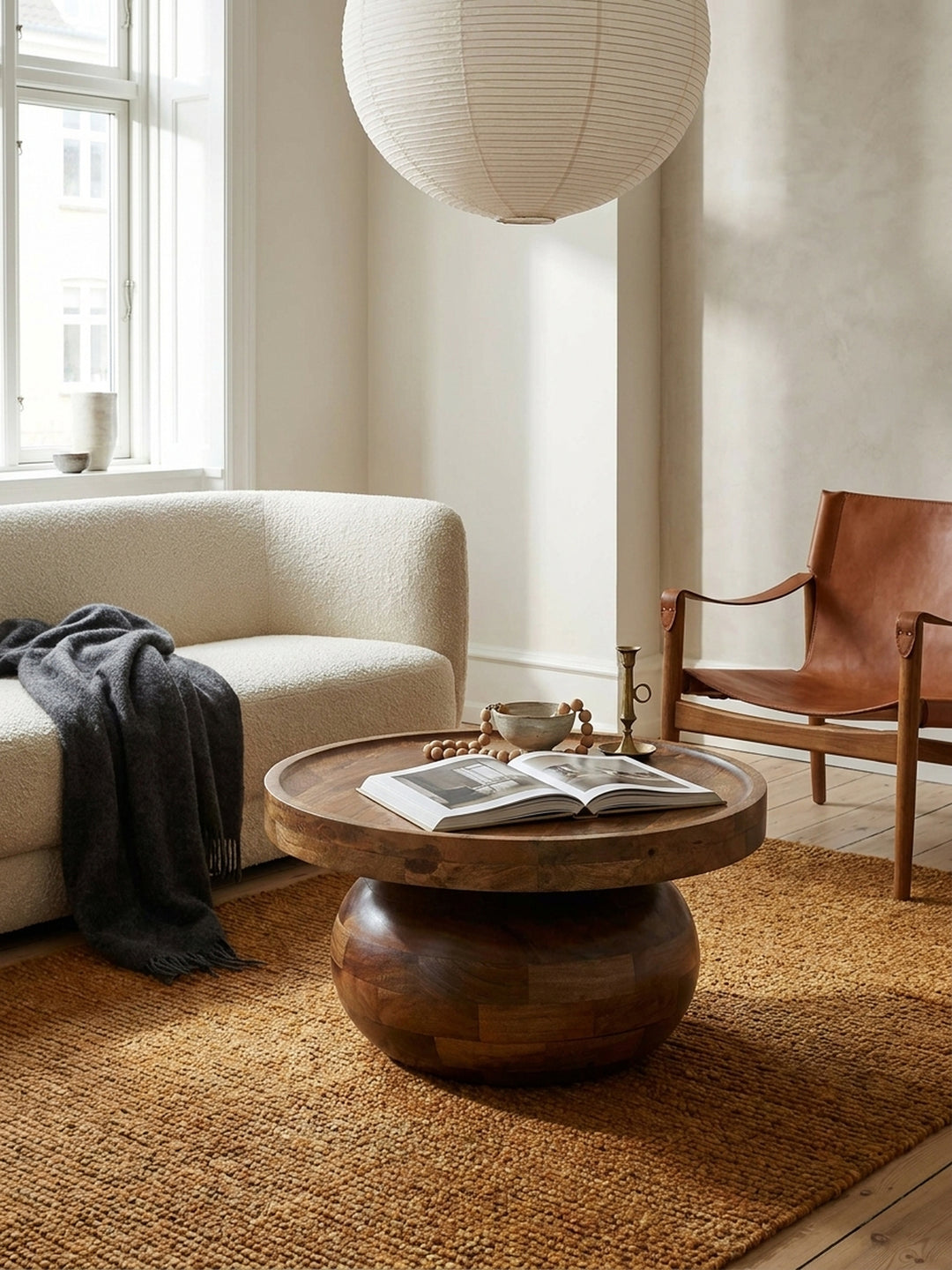 Der niedrige Design-Couchtisch aus Mangoholz neben einem cremefarbenen Sofa, das die warmen Holztöne des Tisches unterstreicht._