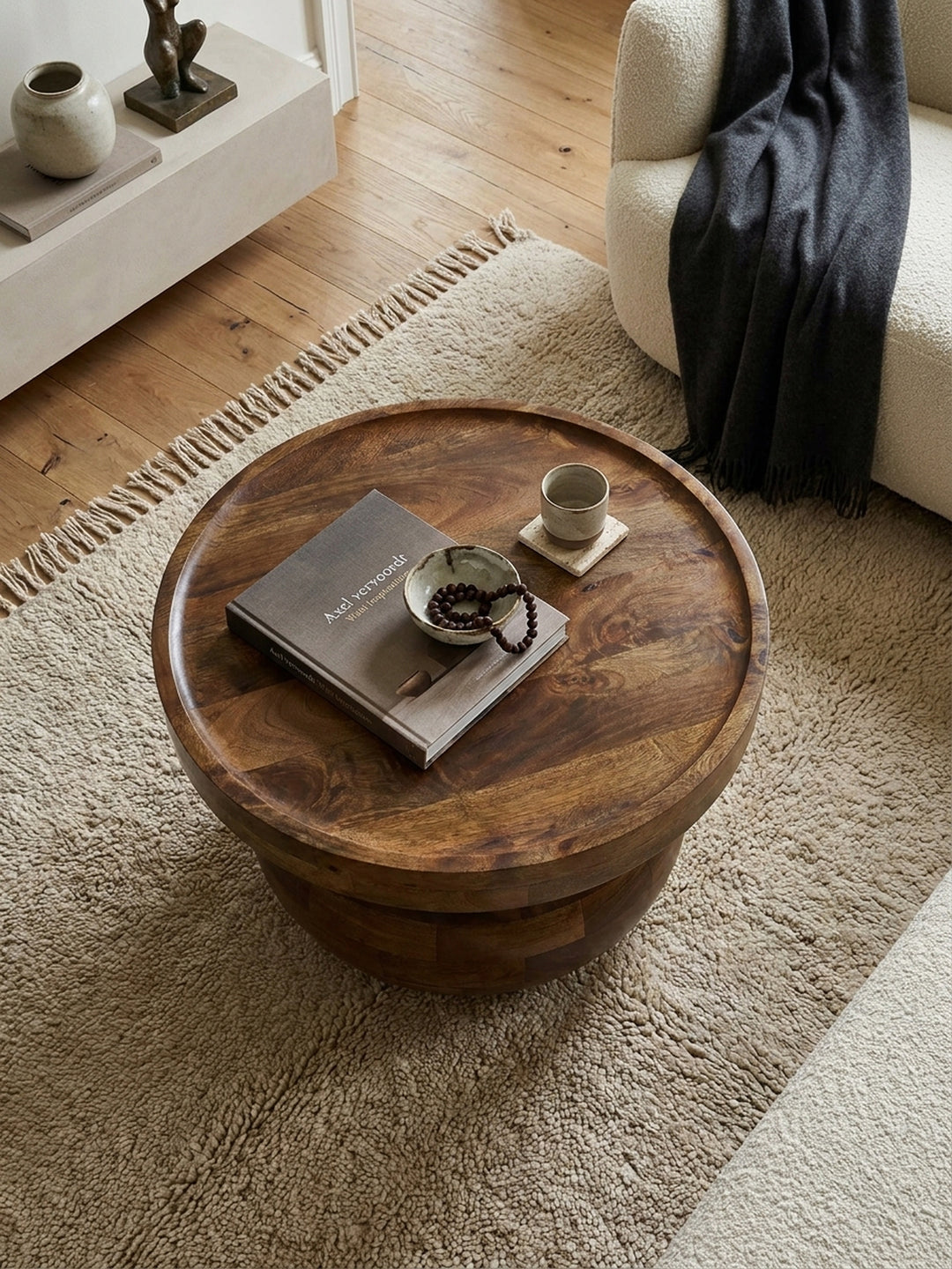 Draufsicht auf den walnussfarbenen Massivholz-Couchtisch mit Tablett-Kante, arrangiert auf einem beigen Wollteppich vor einer modernen Couch._