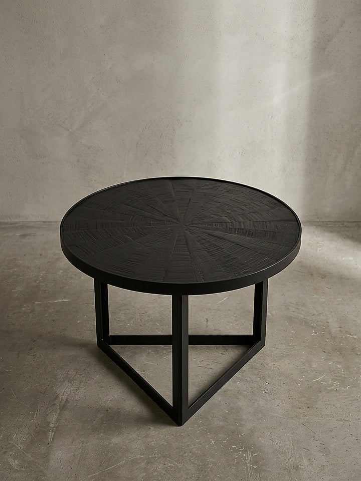 Schrägansicht auf den Loft-Style Couchtisch aus Mangoholz, dessen gefräste Sonnenstrahlen-Optik dezent das Licht reflektiert._