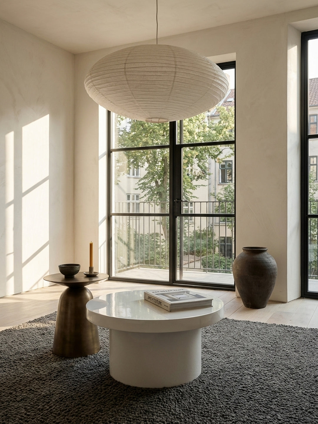 Der kompakte, weiße Kaffeetisch mit 60 cm Durchmesser steht elegant neben einem beigefarbenen Stoffsofa und harmoniert mit dem hellen Holzboden des Raumes._