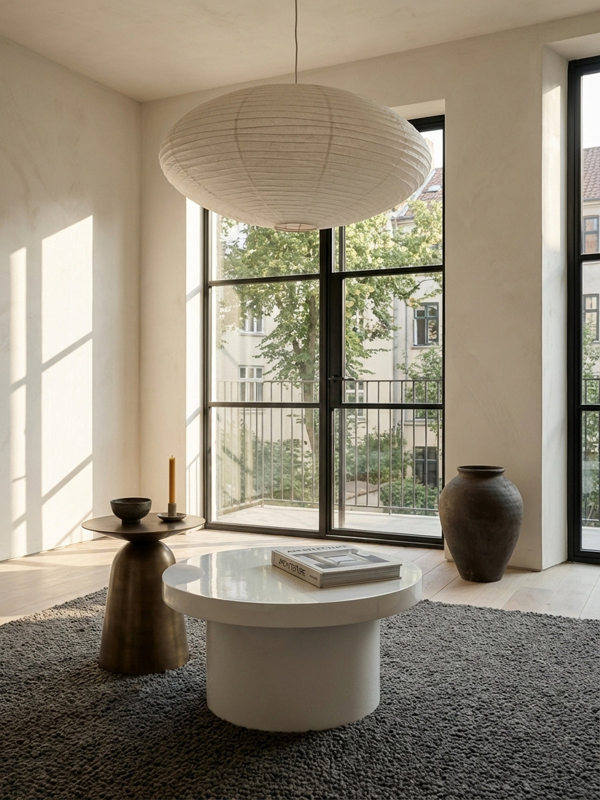 Der kompakte, weiße Kaffeetisch mit 60 cm Durchmesser steht elegant neben einem beigefarbenen Stoffsofa und harmoniert mit dem hellen Holzboden des Raumes._