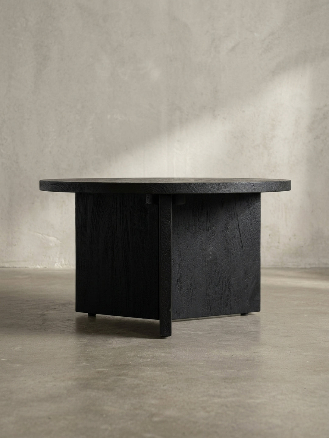 Nahaufnahme eines der drei breiten Holzbeine des Couchtisches, die die hochwertige Verarbeitung und die tiefe, schwarze Farbe des Holzes sichtbar macht._