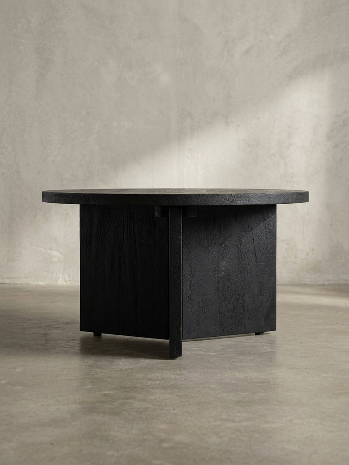 Nahaufnahme eines der drei breiten Holzbeine des Couchtisches, die die hochwertige Verarbeitung und die tiefe, schwarze Farbe des Holzes sichtbar macht._