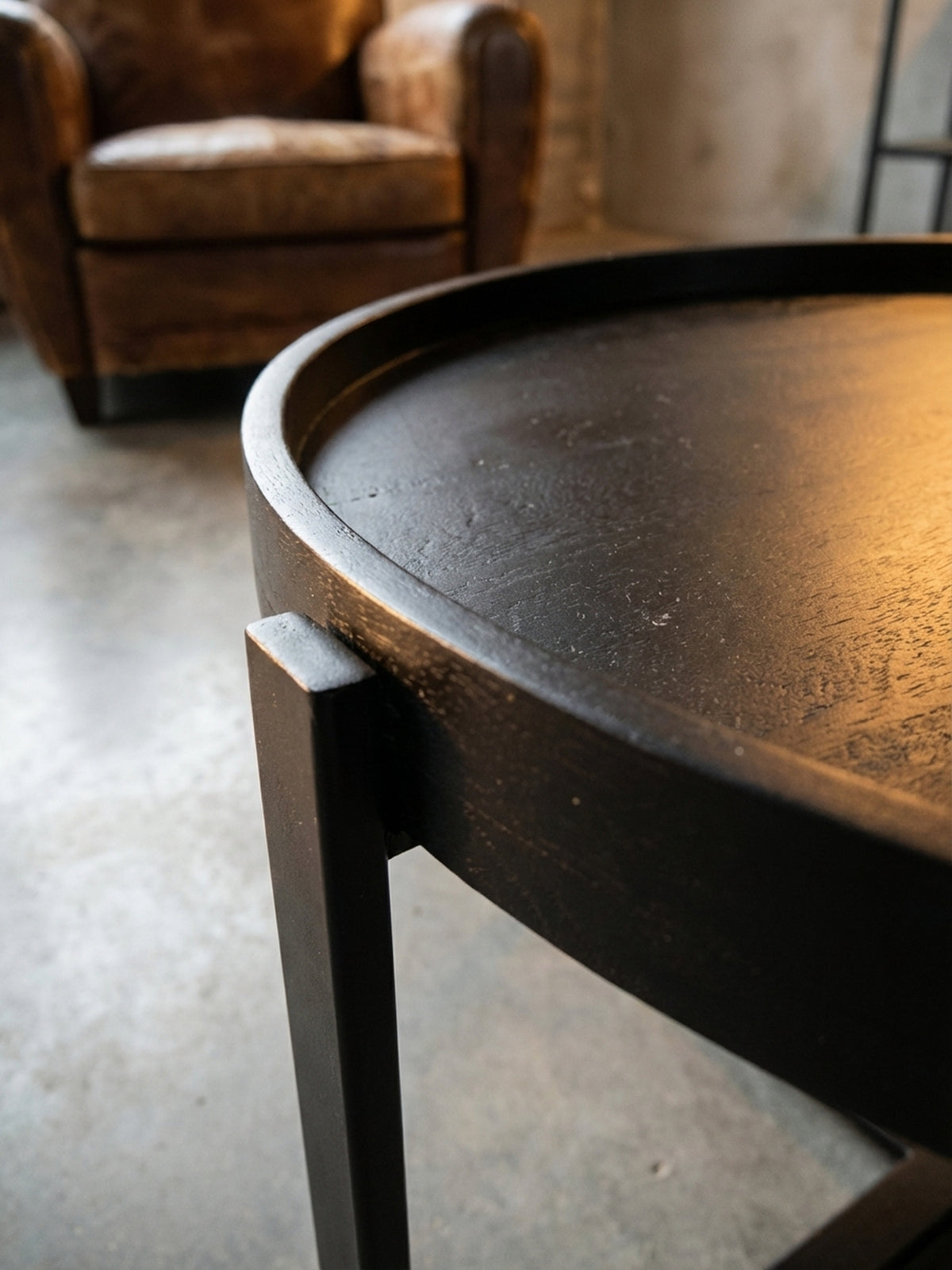 Nahaufnahme der feinen Holzmaserung eines schwarz lackierten Couchtisches aus massivem Mangoholz, die matte Oberflächenstruktur ist deutlich erkennbar._