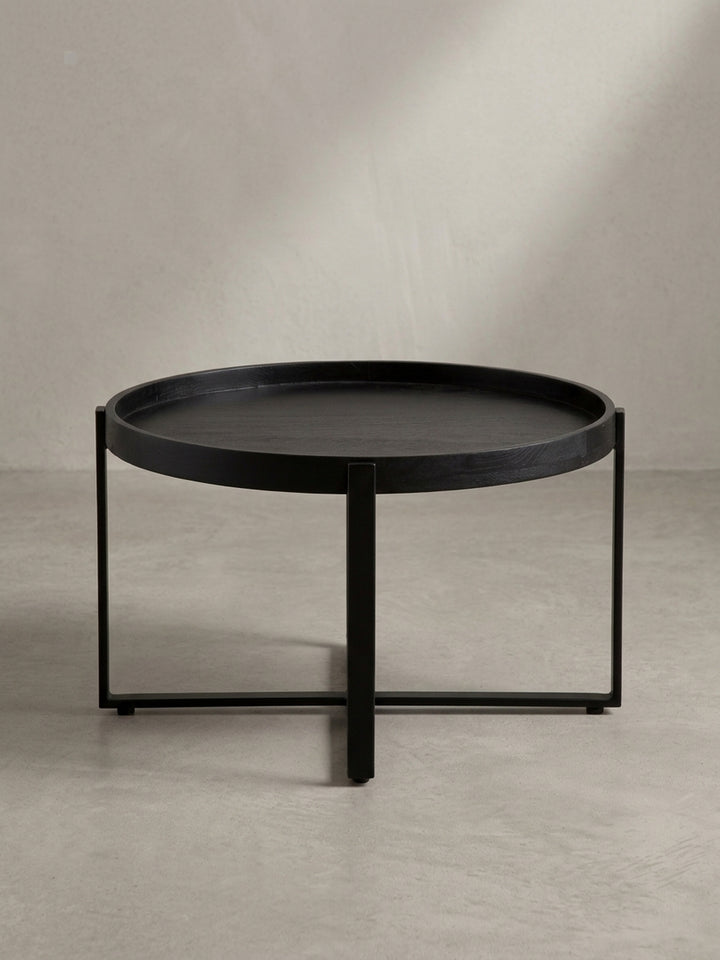 Schräge 3/4-Ansicht des schwarzen Sofatisches, die die Tiefe des erhöhten Randes und die stabile Konstruktion des Metallgestells hervorhebt._