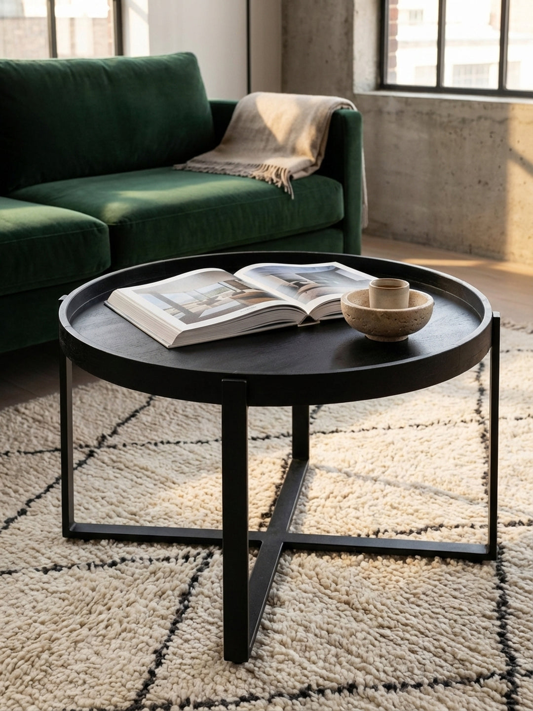 Ein gemütliches Stillleben auf dem runden Sofatisch: Eine schwarze Gusseisen-Teekanne und Gläser auf der matten Tablett-Tischplatte._