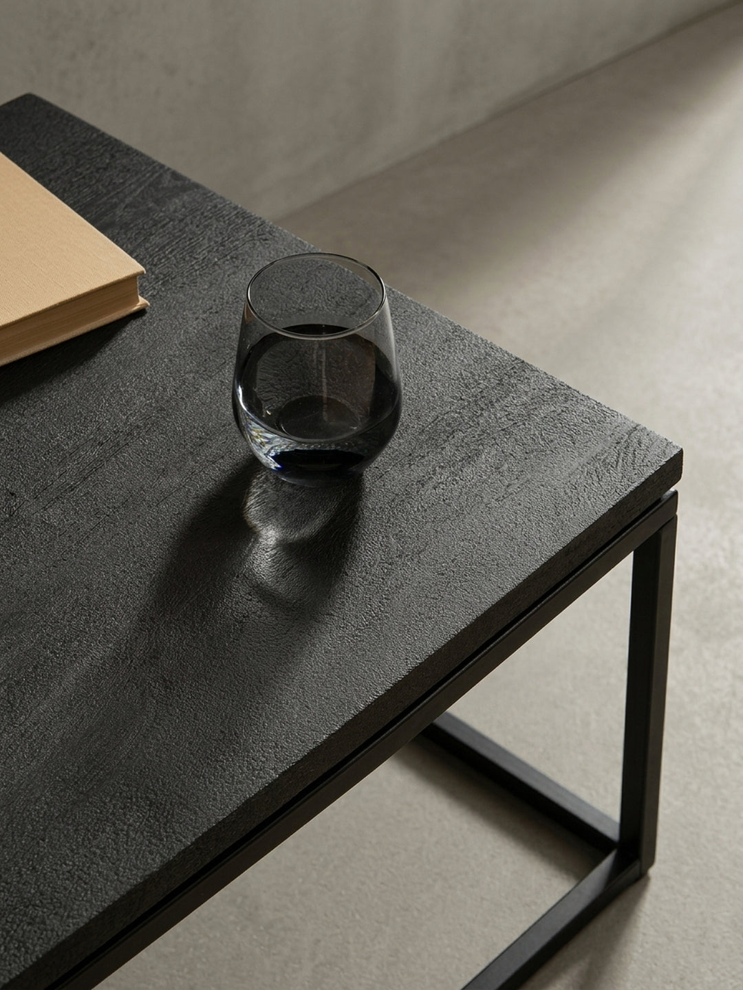 Perspektivische Aufnahme des schwarzen Massivholz-Couchtisches, die die Tiefe der sandgestrahlten Oberfläche und die matte Optik einfängt._