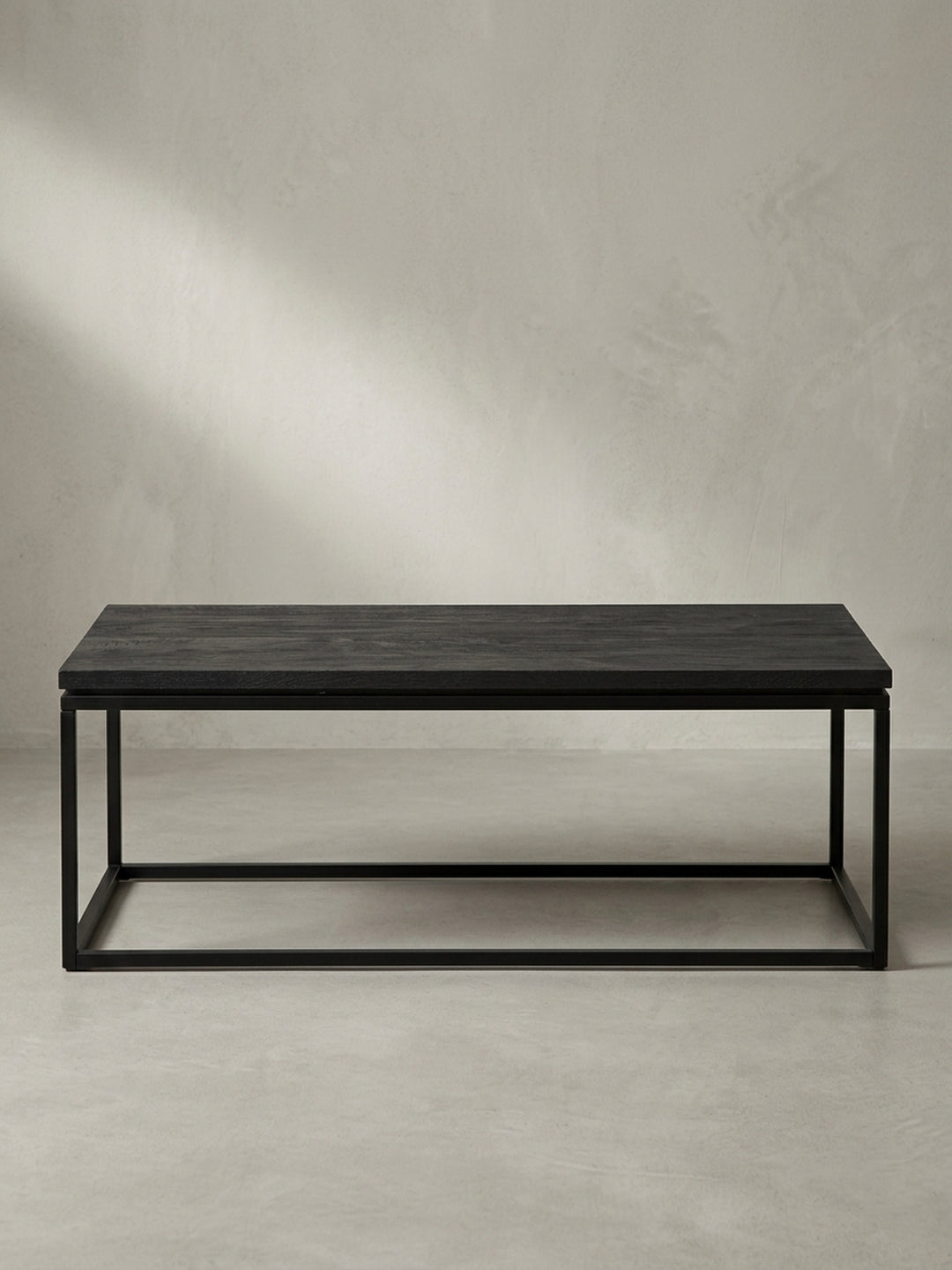Schräge 3/4-Ansicht des Design-Sofatischs, die die klare Linienführung des schwarzen, pulverbeschichteten Eisengestells betont._
