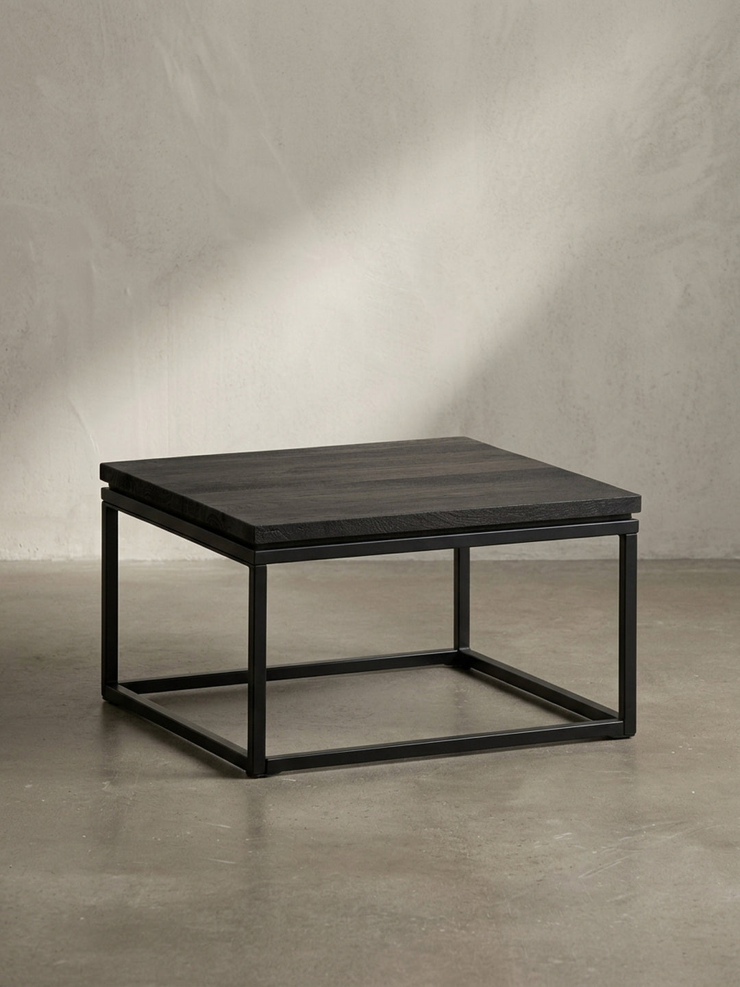 Design-Couchtisch aus schwarzem Holz und Metall in der Dreiviertelansicht, die die klare, kubische Form und die robuste Konstruktion hervorhebt._