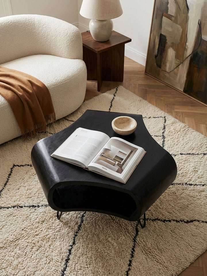 Von oben fotografierter Design-Couchtisch in organischer Form, zentral platziert vor einem cremefarbenen Bouclé-Sofa in einem minimalistisch eingerichteten Altbau-Wohnzimmer._