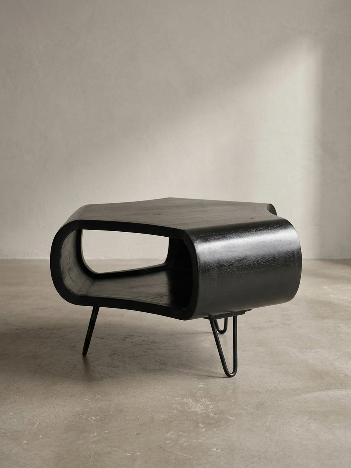 Alternative Perspektive auf den schwarzen Wohnzimmertisch, die den Kontrast zwischen dem voluminösen Holzkörper und den leichten, luftigen Beinen im Mid-Century-Stil betont.