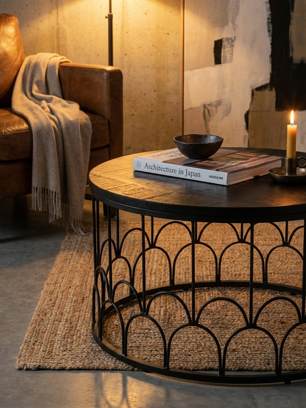 Gemütliche Kaffeepause am runden schwarzen Sofatisch, dekoriert mit einem schweren Architektur-Bildband und einer Gusseisen-Teekanne im lichtdurchfluteten Loft._
