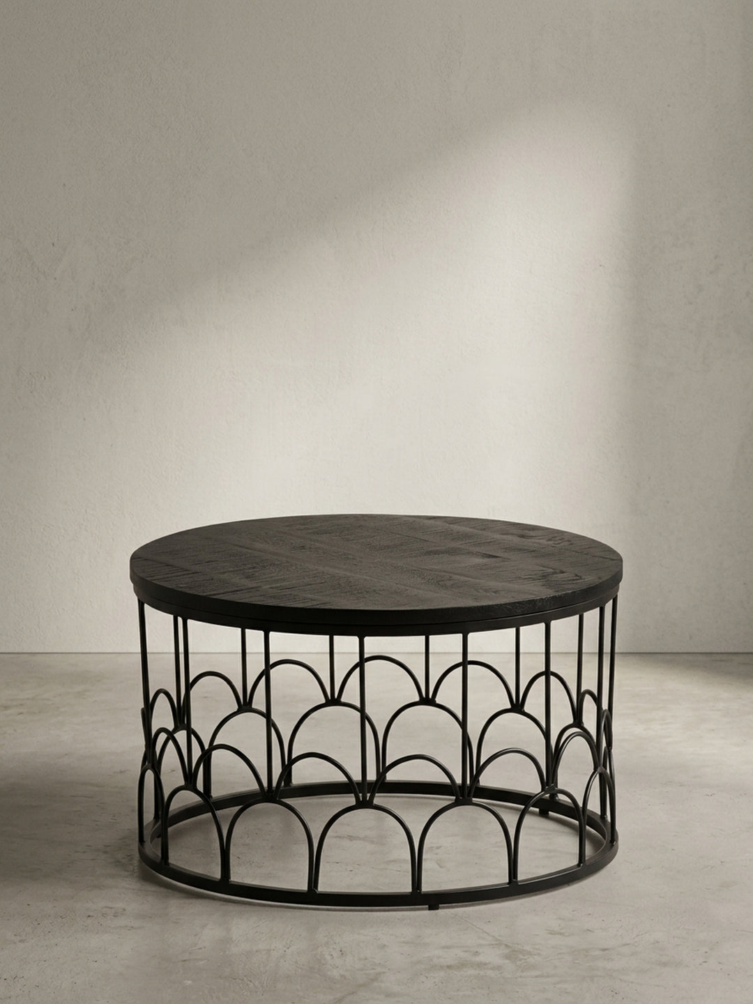 Runder Couchtisch aus schwarzem Mango Massivholz 60x60x36 cm mit dekorativem Eisengestell aus eleganten Rundbögen in Frontalansicht vor neutralem weißen Hintergrund._