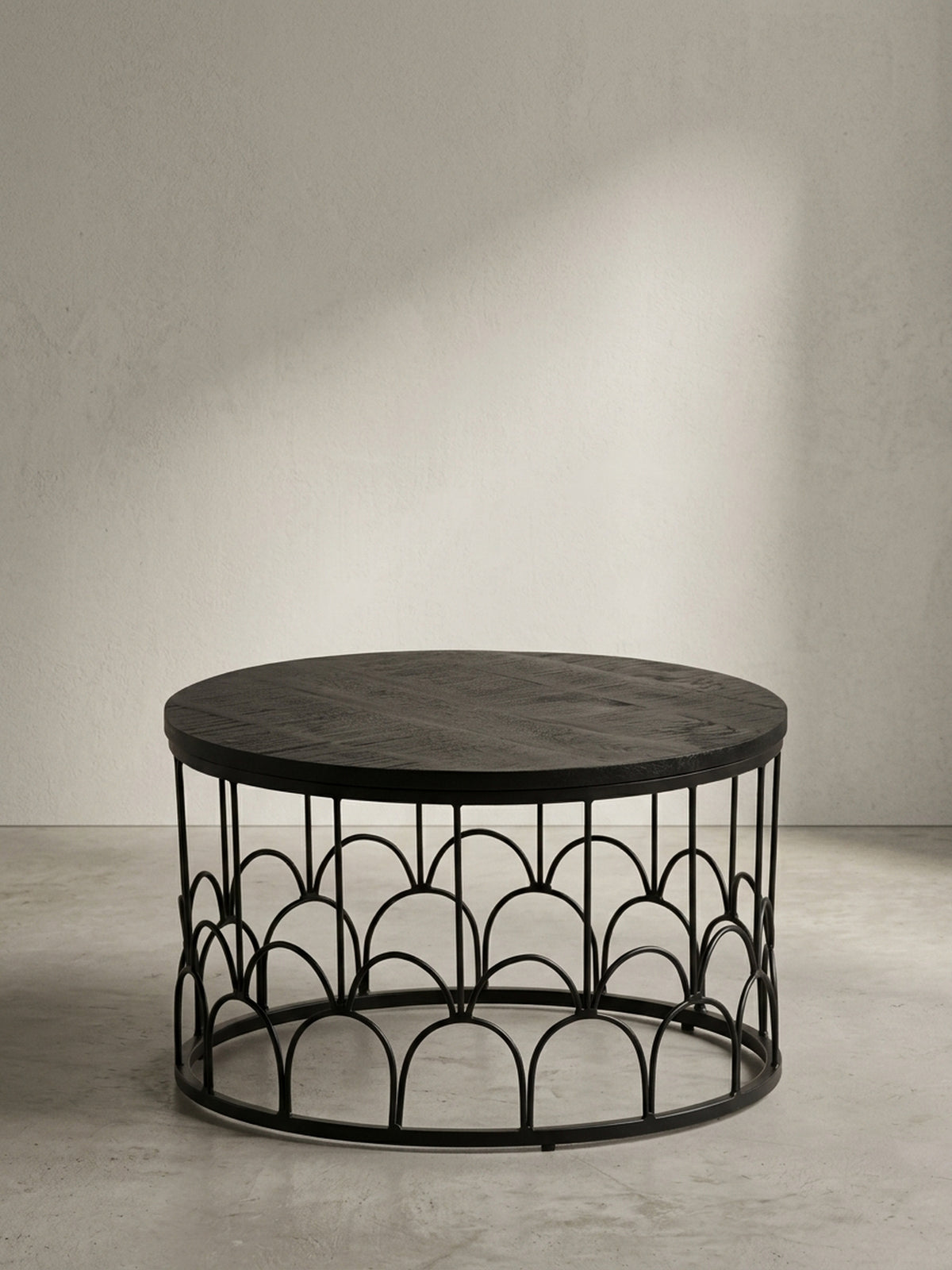 Runder Couchtisch aus schwarzem Mango Massivholz 60x60x36 cm mit dekorativem Eisengestell aus eleganten Rundbögen in Frontalansicht vor neutralem weißen Hintergrund.