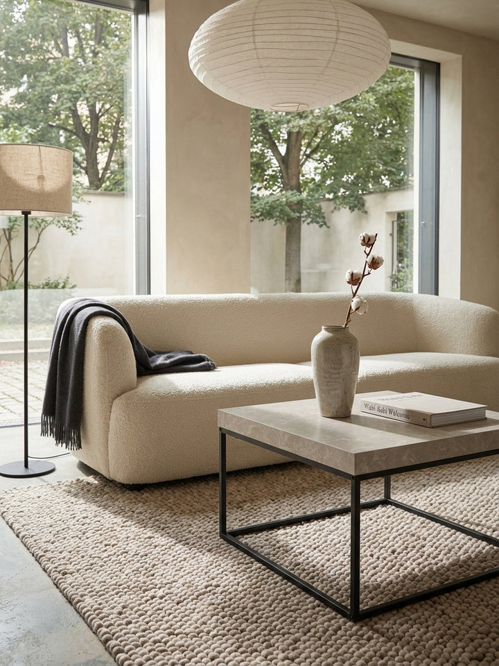Der 60x60 cm große Wohnzimmertisch in Steinoptik harmoniert mit einem cremefarbenen Sofa und einem Beistelltisch aus dunklem Holz._