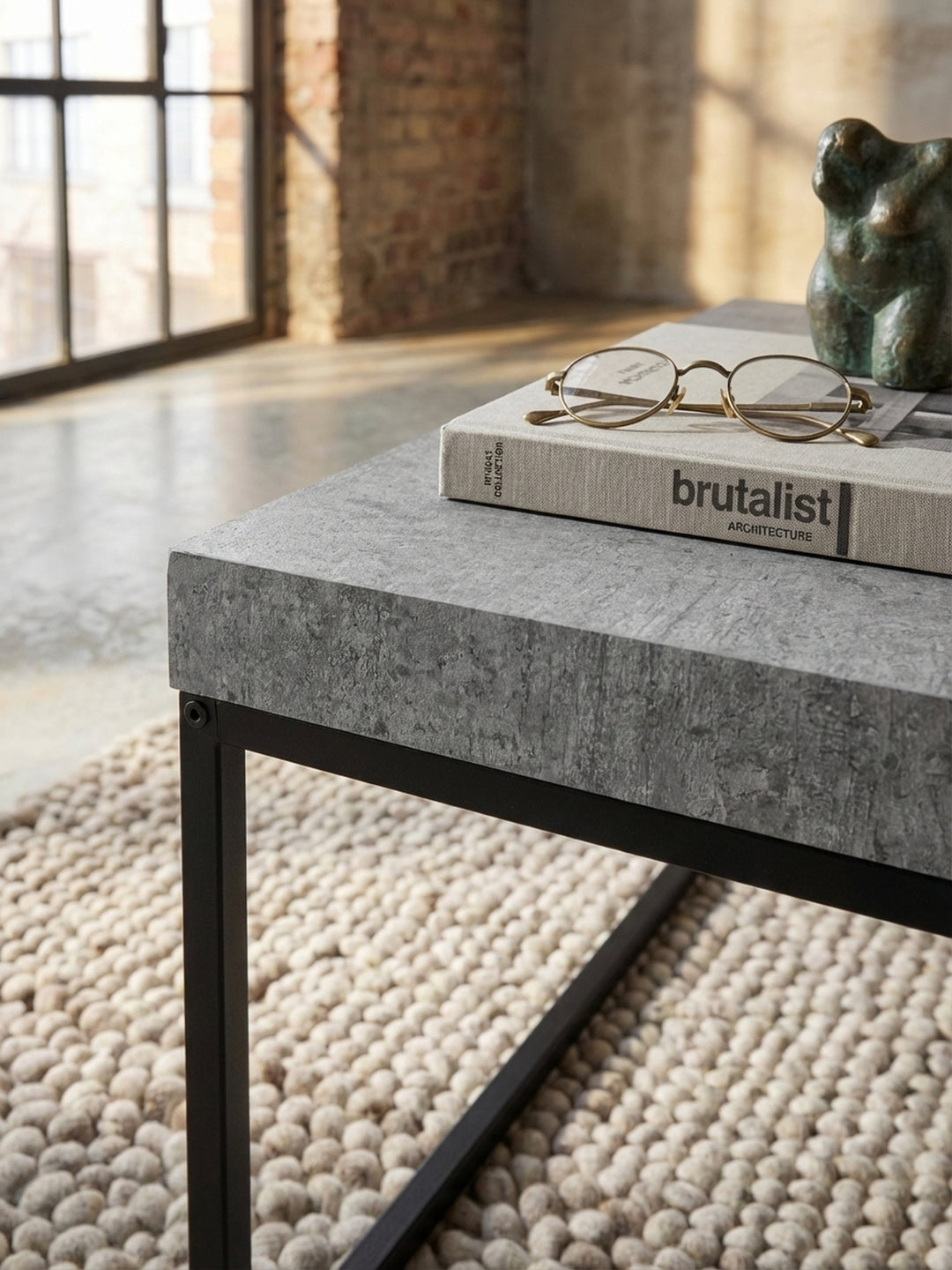 Detailaufnahme der texturierten Oberfläche eines grauen Couchtisches in Beton-Optik, die die feine Maserung und das matte Finish des Materials zeigt._