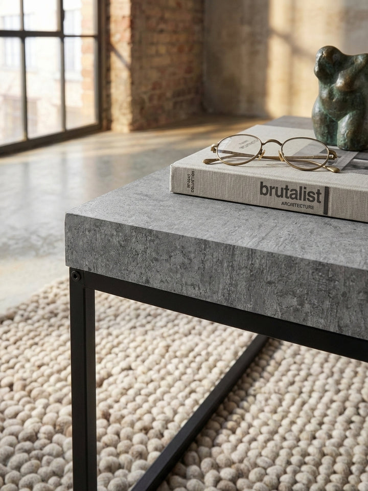 Detailaufnahme der texturierten Oberfläche eines grauen Couchtisches in Beton-Optik, die die feine Maserung und das matte Finish des Materials zeigt._