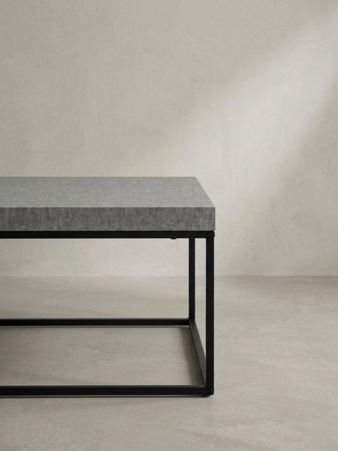 Alternativer Blickwinkel auf den Loungetisch in Beton-Look, der die geometrische Klarheit des Designs und die schwebende Optik der Tischplatte unterstreicht._