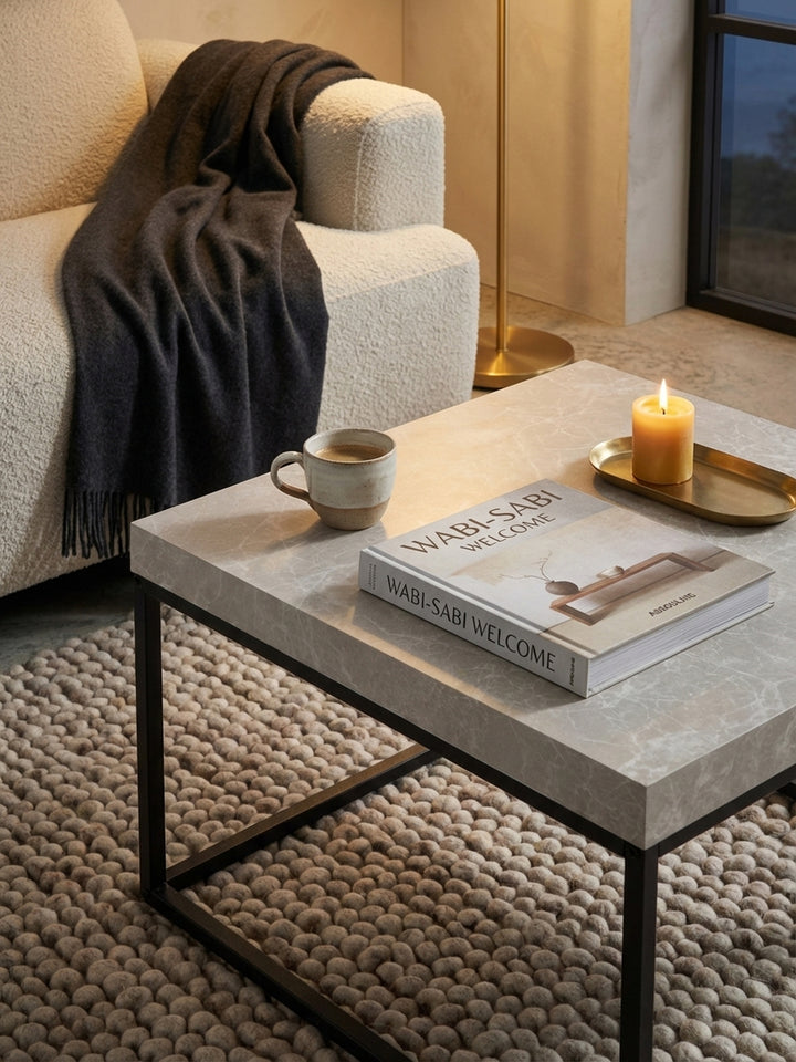 Ein Kaffeetisch mit einem offenen Architekturbuch und einer handgefertigten Keramikvase, die ein gemütliches Ambiente im modernen Wohnzimmer schafft._