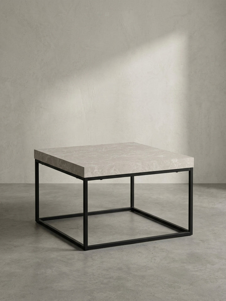 Seitenansicht des modernen Kaffeetisches, die das minimalistische, kubische Gestell aus schwarzem Metall und die schwebende Wirkung der Platte zeigt._
