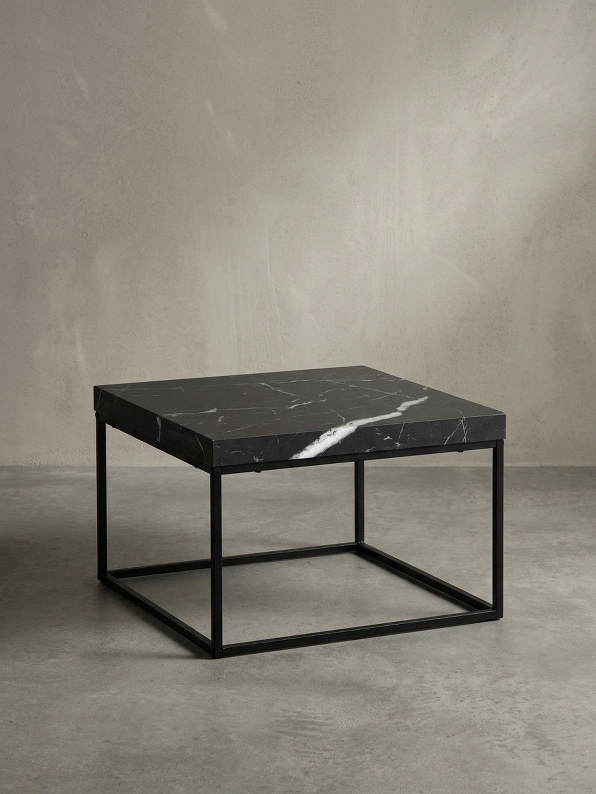 Sofatisch aus beschichtetem Holzwerkstoff und Metall in Schwarz von schräg oben betrachtet, zeigt die markante 5 cm dicke kubische Tischplatte._