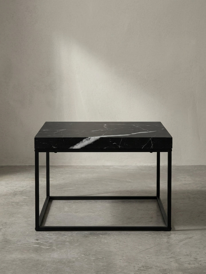 Alternative Perspektive des kompakten 60x60 cm großen Beistelltisches betont die streng geometrische Silhouette des offenen matten Gestells._