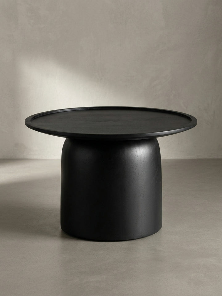 Nahaufnahme der sorgfältig gearbeiteten, erhöhten Kante des schwarzen Massivholz-Couchtisches, ideal als Ablage._