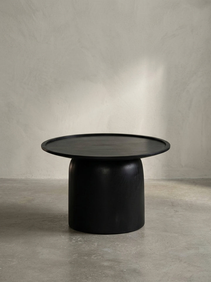 Frontansicht des runden, schwarzen Couchtisches aus massivem Mangoholz mit Trommelgestell auf weißem Hintergrund._