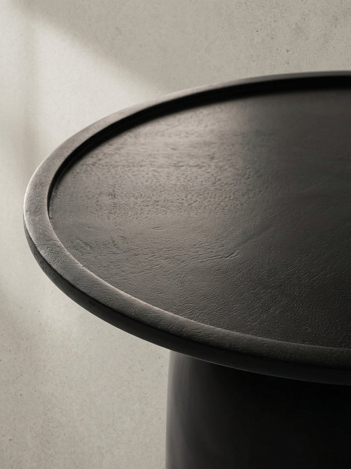 Der runde schwarze Mangoholz-Kaffeetisch aus einer leicht erhöhten Perspektive, die seine großzügige 60 cm Tischplatte betont._