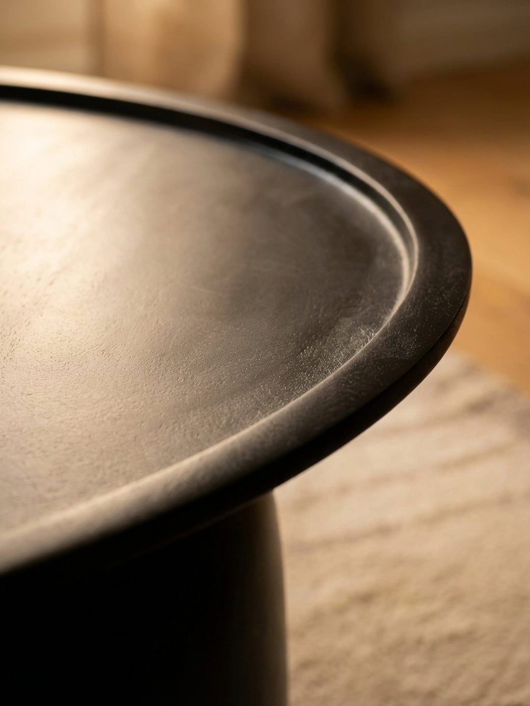 Detailaufnahme der feinen Holzmaserung eines schwarz lackierten Couchtisches aus Mango Massivholz mit matter Oberfläche._