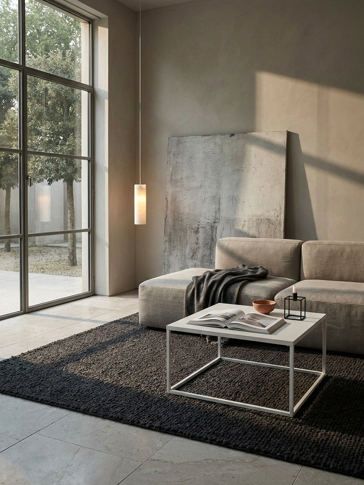Minimalistischer Beistelltisch aus weißem Stahl kombiniert mit einem dunklen Teppich und hellem Kalksteinboden im modernen Lounge-Bereich_