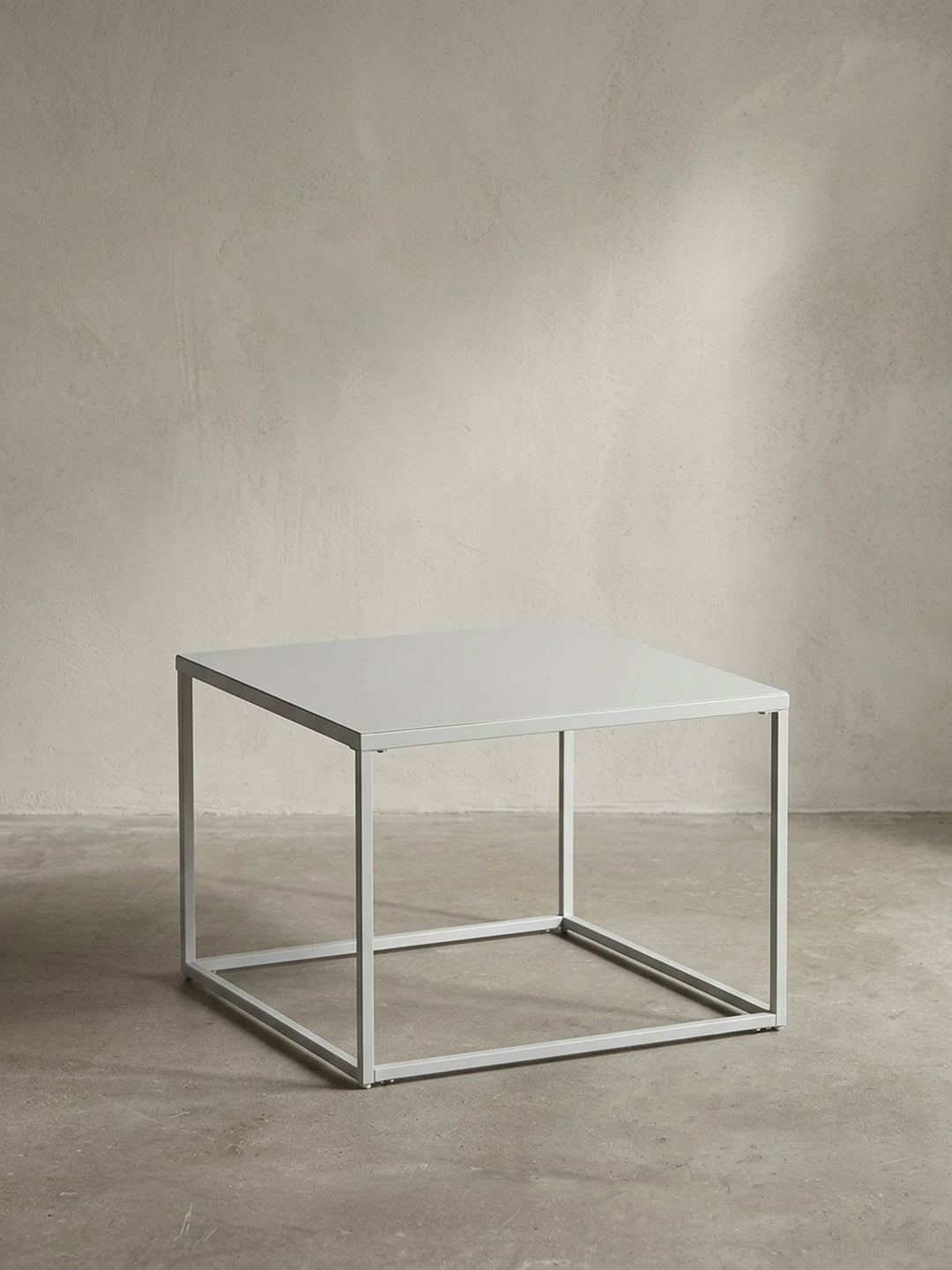 Quadratischer Couchtisch aus durchgehend weiß lackiertem Stahl in der Größe 60x60 cm mit klaren geometrischen Linien vor neutralem Hintergrund_