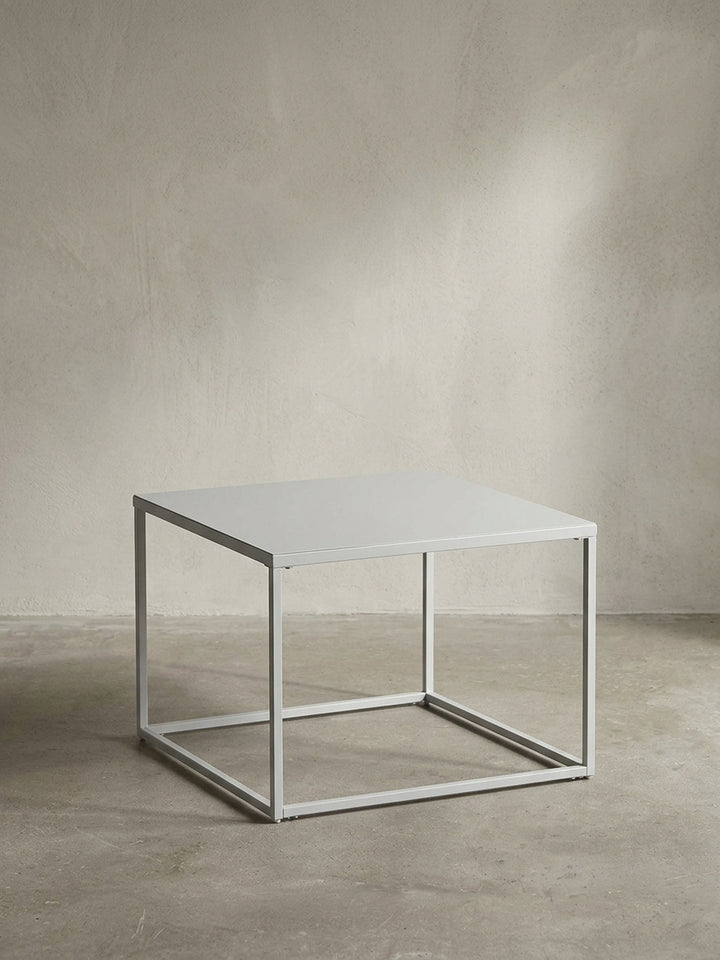 Quadratischer Couchtisch aus durchgehend weiß lackiertem Stahl in der Größe 60x60 cm mit klaren geometrischen Linien vor neutralem Hintergrund_